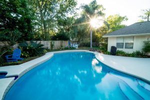 Bright blue pool in the backyard of a home. Remodeled.