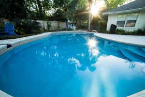 Bright blue pool in the backyard of a home. Remodeled.