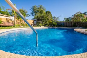 Close up of bright blue pool in the backyard of a home.