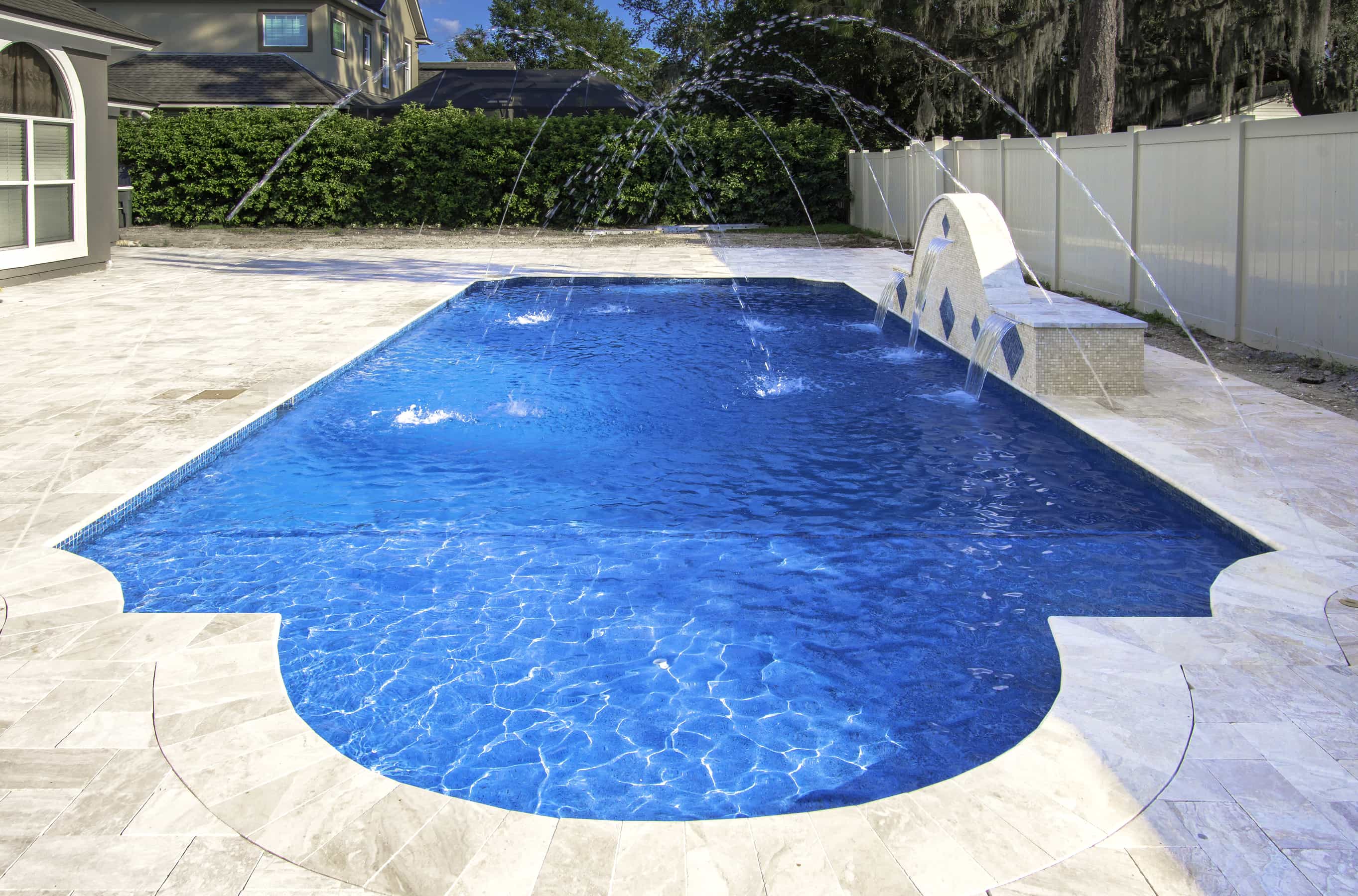 Luxury bright blue pool in the backyard of a home with beautiful tiles. Waterfall pouring water.